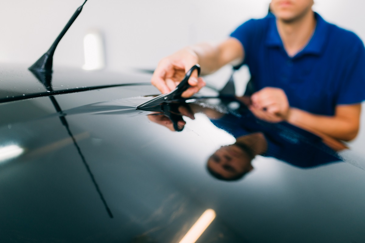 Worker with scissors, car tinting installation