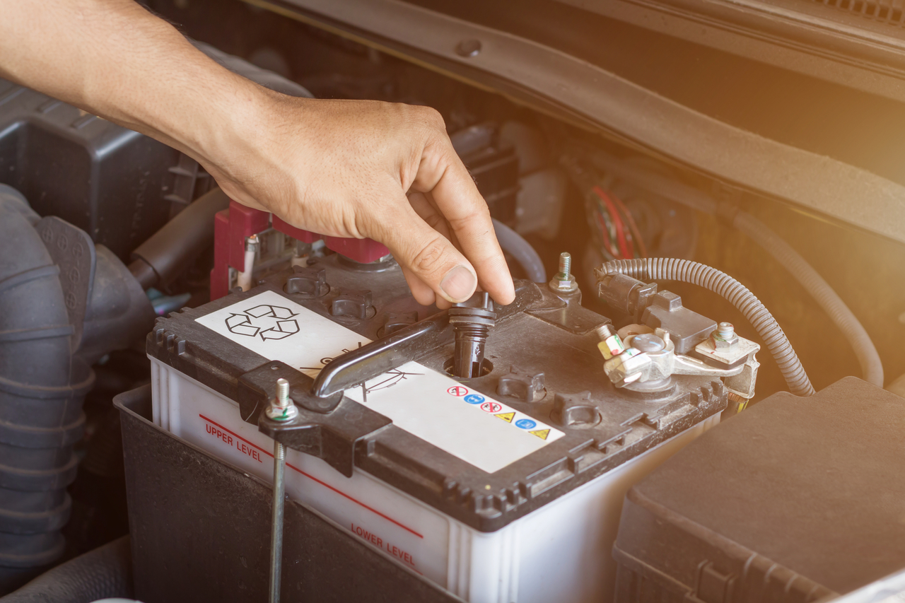 A hand inspecting a car battery