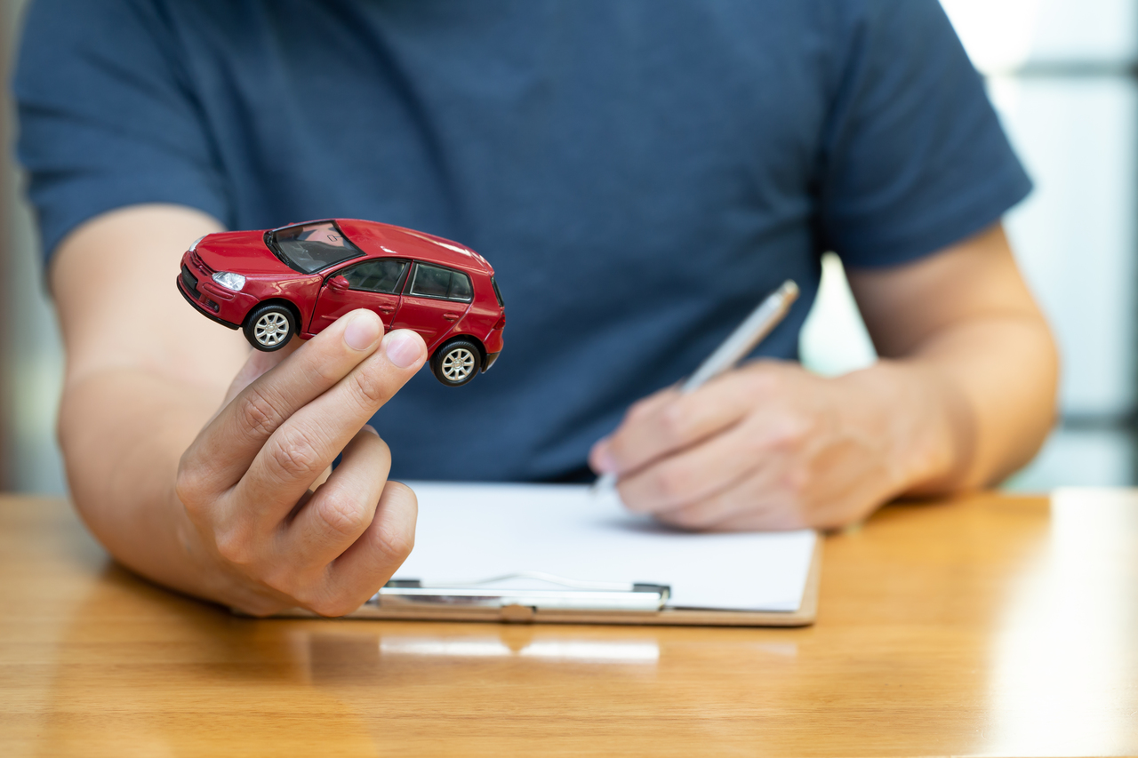Man holding toy car signing a contract