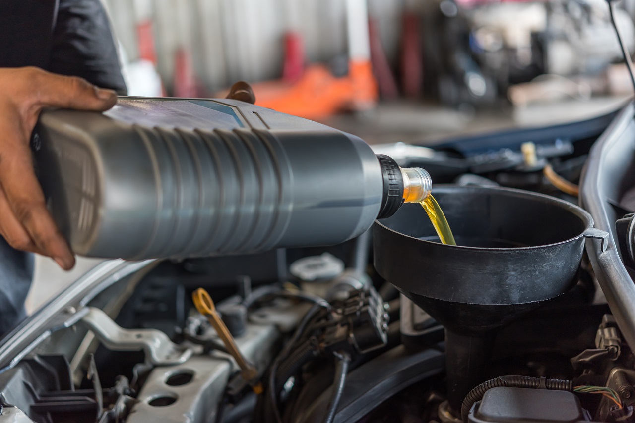 Car mechanic fills a fresh lubricant engine oil