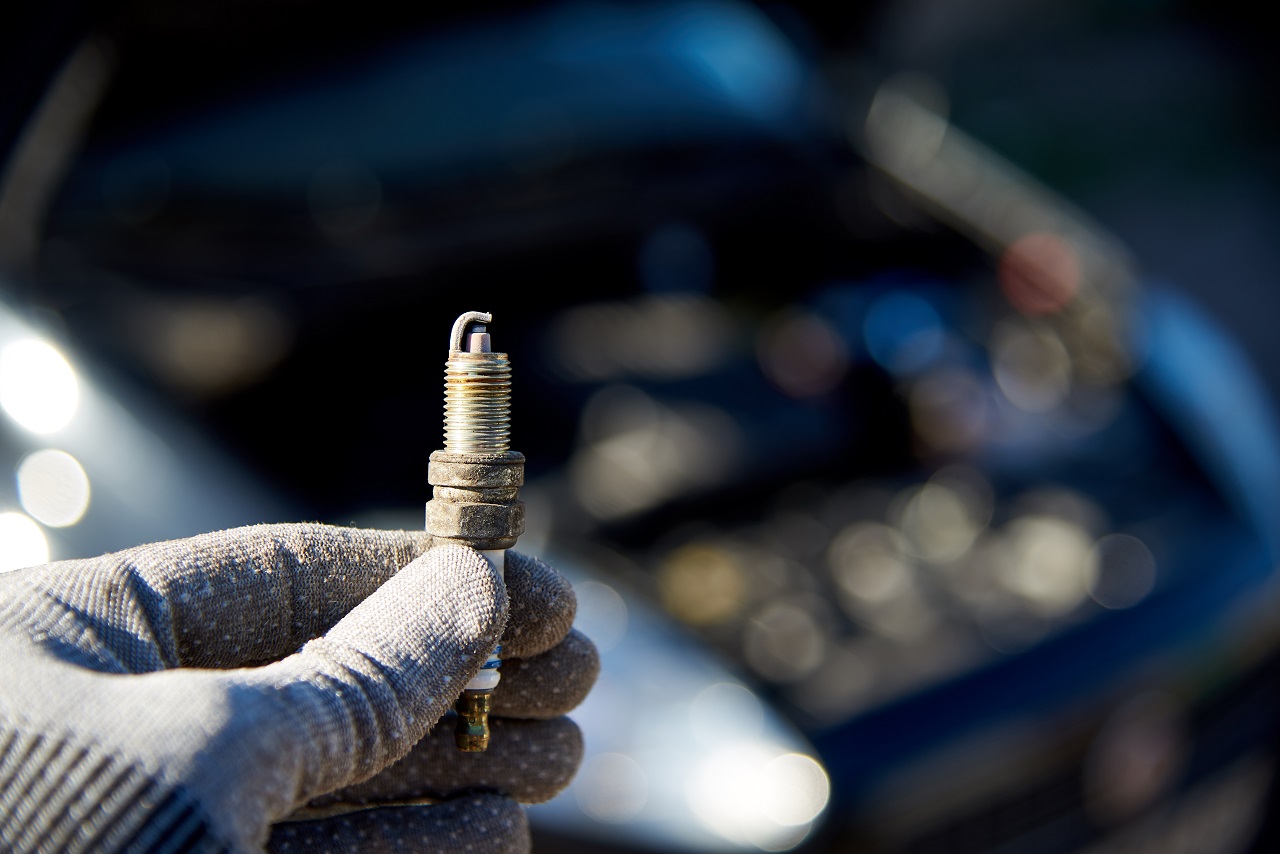 A hand holding up a hybrid car's spark plug